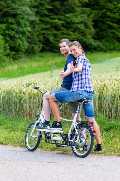 Couple riding tandem bike together in the country