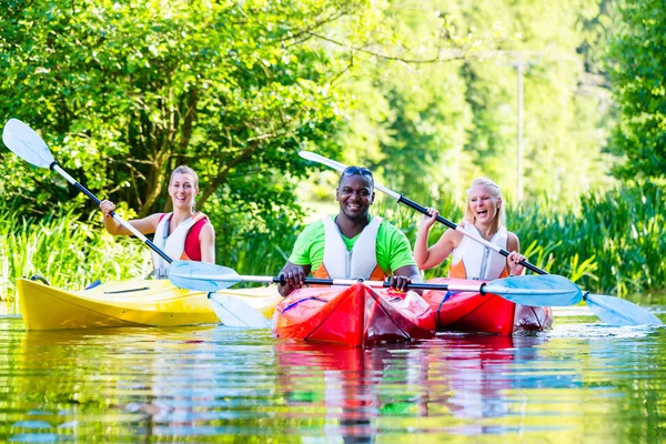 Friends paddling with canoe on forest river