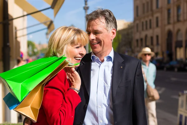 Mature couple strolling through city shopping in spring