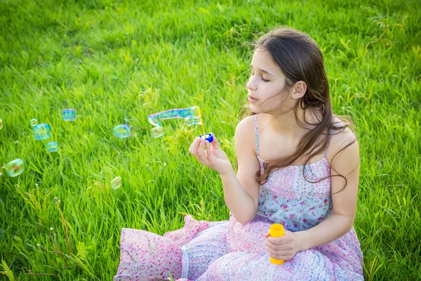 Girl blowing up the soap bubbles on green lawn