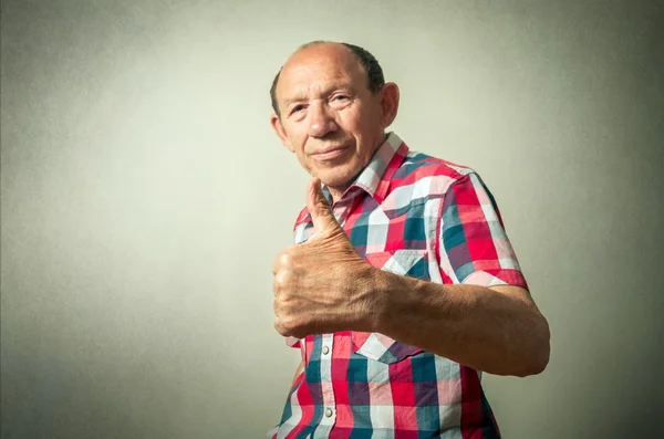 Portrait of the funny senior man doing thumbs up