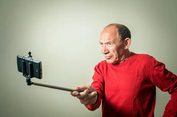 Portrait of the funny senior man taking selfie
