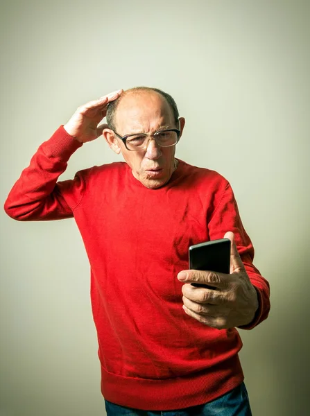 Portrait of the funny senior man looking on phone