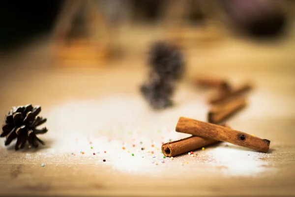 Cinnamon sticks on wood table with bundles of cinnamon in soft focus in background. Macro with extremely shallow dof.