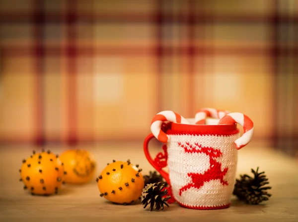 Insulated wool cloth mug with embroidered deer on the wooden table mug with tangerines and a candy