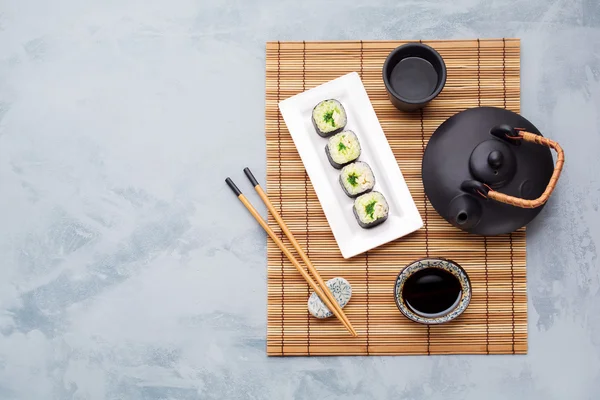 Teapot, green tea, sushi and soy sauce.