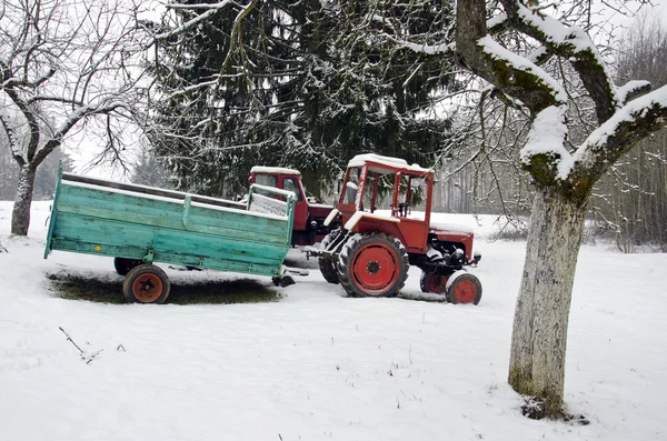 Old small agriculture tractor in winter farm garden