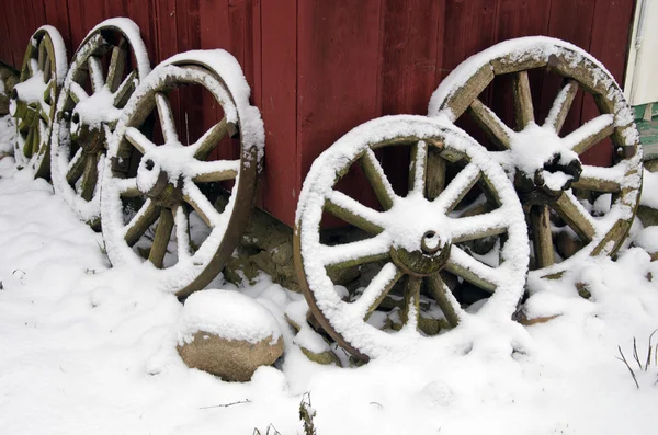 Antique horse carriage wheels near farm house and snow