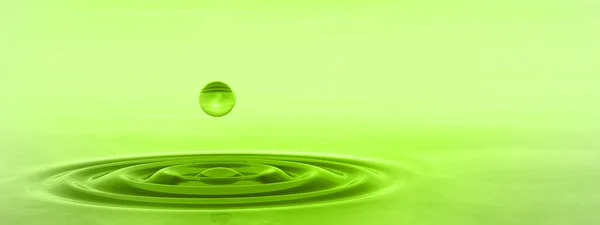 Green liquid drop falling in water