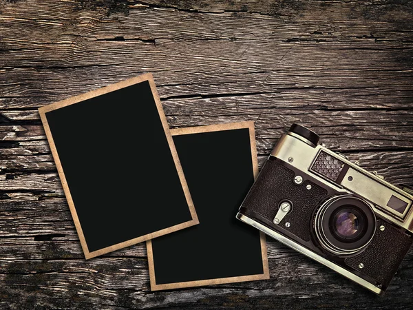 Old vintage camera and photos on a wooden background