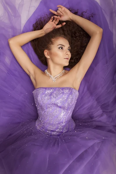 Portrait of a beautiful girl in a purple dress lying on the floor