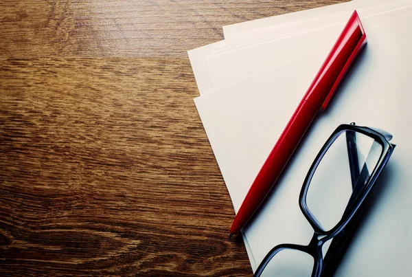 Pen and reading glasses on blank paper