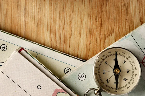 Vintage Compass on Wooden Table with Folded Maps