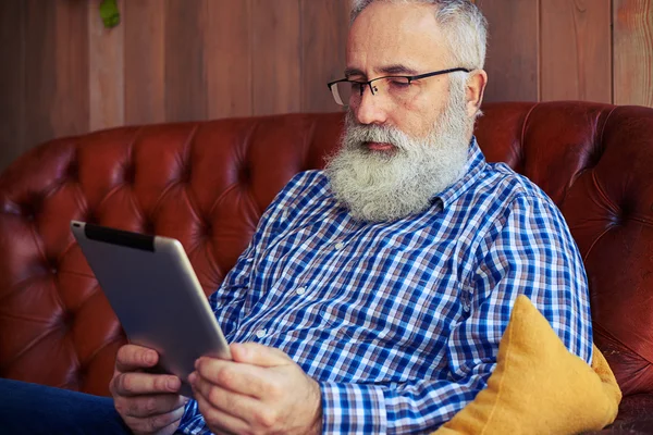 Bearded man sitting on sofa and reading news