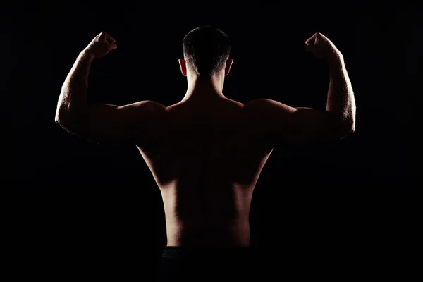 Back of athletic man showing muscles on black background