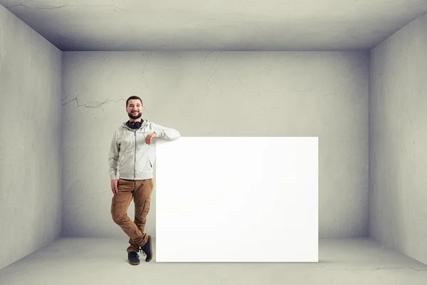 Man near huge poster in room with white walls