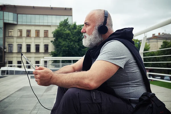 Sideview portrait of stylish aged man listening to music on a si