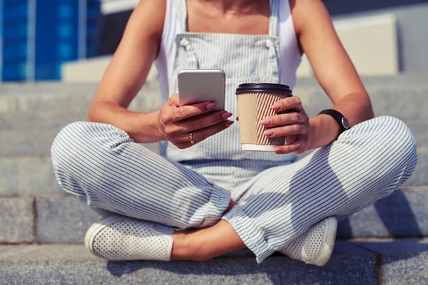 Close-up of slim woman sitting with crossed legs with coffee an