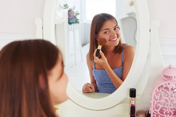 Modern girl applying powder on the face using makeup brush