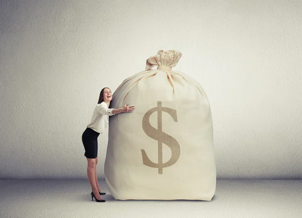 Woman embracing big bag with money