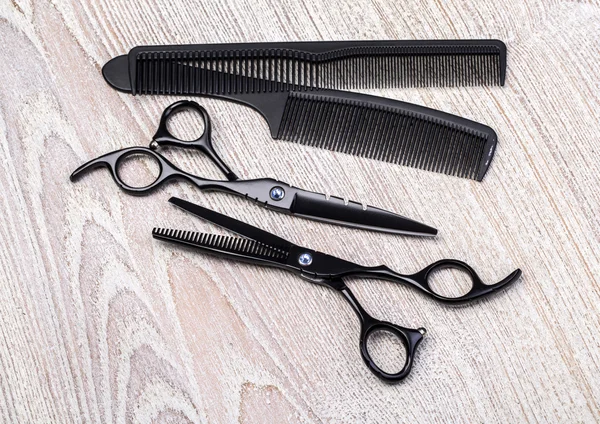 Scissors and comb on white rustic woode