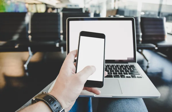 Young Man use Notebook or Laptop Computer and phone in the airport.