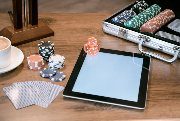 Poker set in a metallic case with tablet over wooden table, retro filtered image