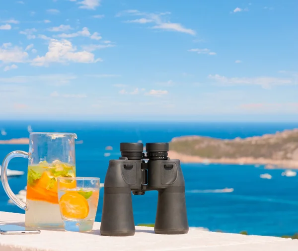 White paid telescope stands on sea coast over blue sky background