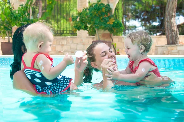 Two happy little girl with mothers in swimming pool