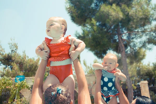 Two happy children with mothers playing in the pool