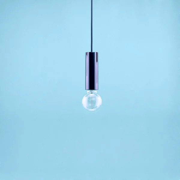 Decorative antique edison style filament light bulb on light blue background. Filtered image