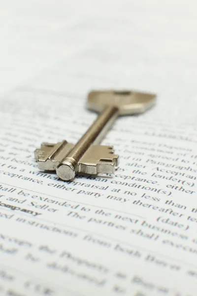 House key lying on a contract of house sale lease insurance or mortgage in a real estate concept