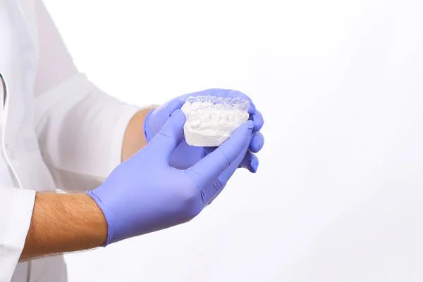 Close-up shot of doctors hands in gloves holding silicone mouth guard. Teeth care