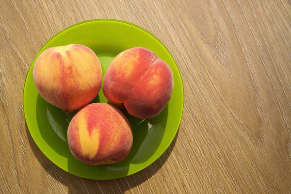 Healthy organic food, healthy fruits peaches. Ripe and tasty and juicy peaches lie on a plate on a wooden table