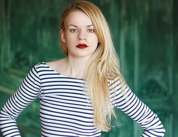Blonde with red lips in striped shirt on a green background
