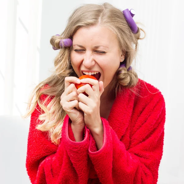 Girl in red robe and curlers eating an apple