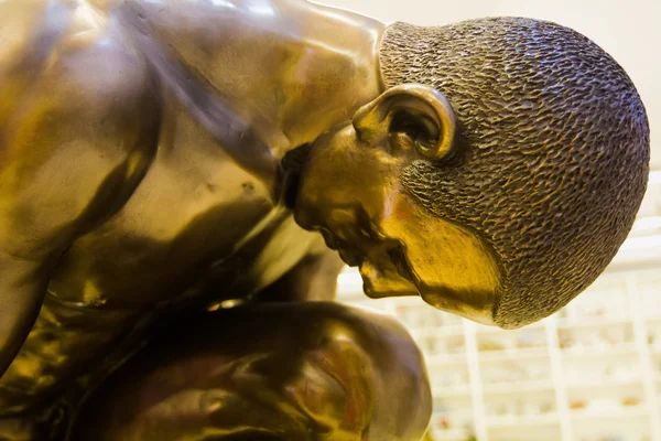 Sculpture of a person crouching in bronze