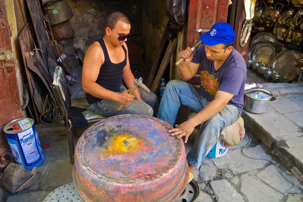 Young moroccan men forging a copper pot