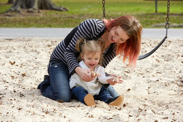 Mother and daughter playing with sand in park