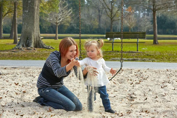 Mother and daughter playing with sand in park