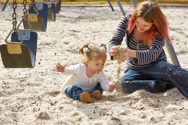 Mother and daughter playing with sand in park