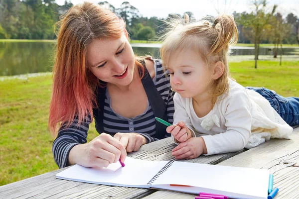 Mother and daughter drawing colors in a park