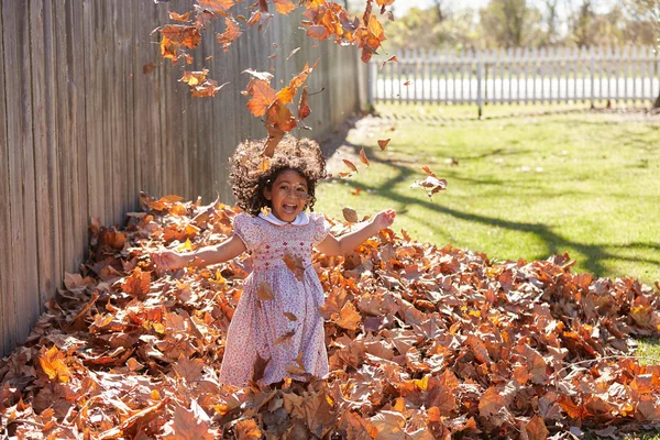 Toddler kid girl playing with autumn leaves