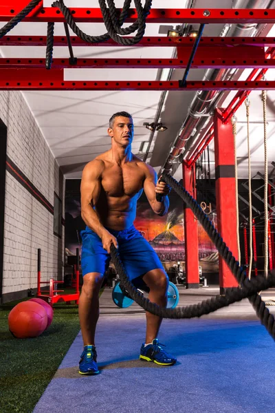 Battling ropes man at gym workout exercise