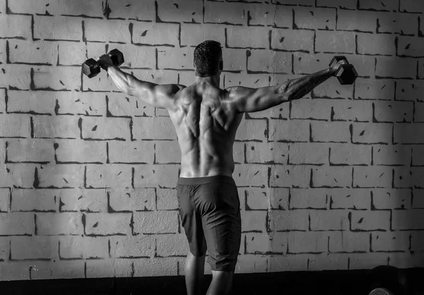 Gym man rising hex dumbbells weightlifting rear