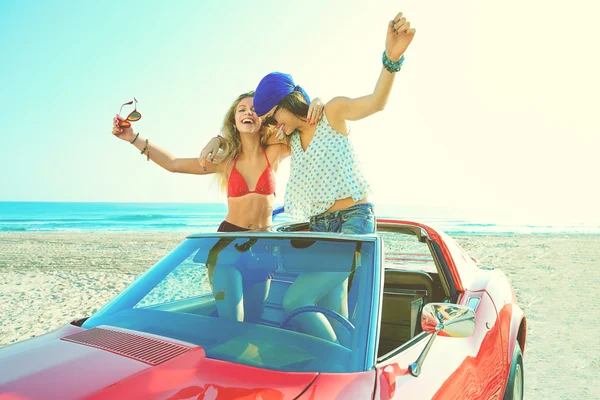 Beautiful party girls dancing in a car on the beach