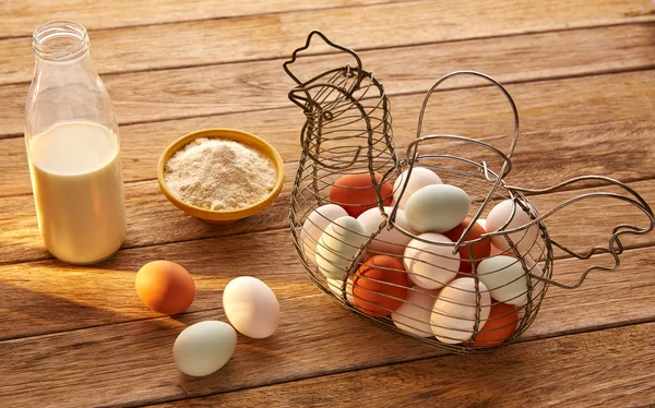 Eggs flour and milk in a vintage hen shape basket on wood