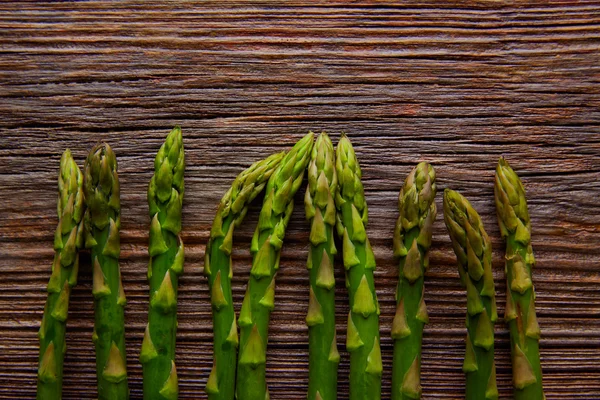 Asparagus raw vegetables in a row on aged wood