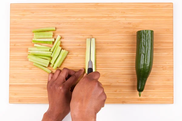 African  American womans hand slicing cucumber - Flat lay