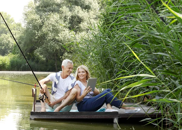 Mature couple fishing while sitting on pier